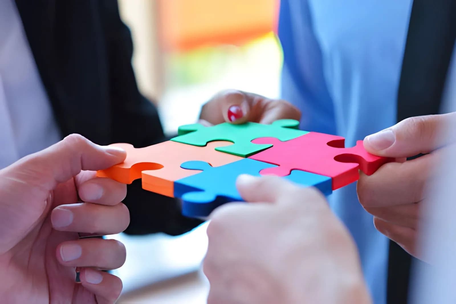Three people fitting colorful jigsaw puzzle pieces together